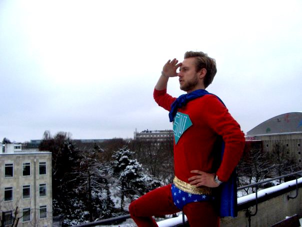 SU-MAN - Iført stramt rødt heltetøj skuer Studenterrådets utrættelige forsvarer for SU'en ud over byens tage. SU-man er blevet lanceret vinteren 2010 i en kampagne for bedre økonomiske vilkår for studerende.