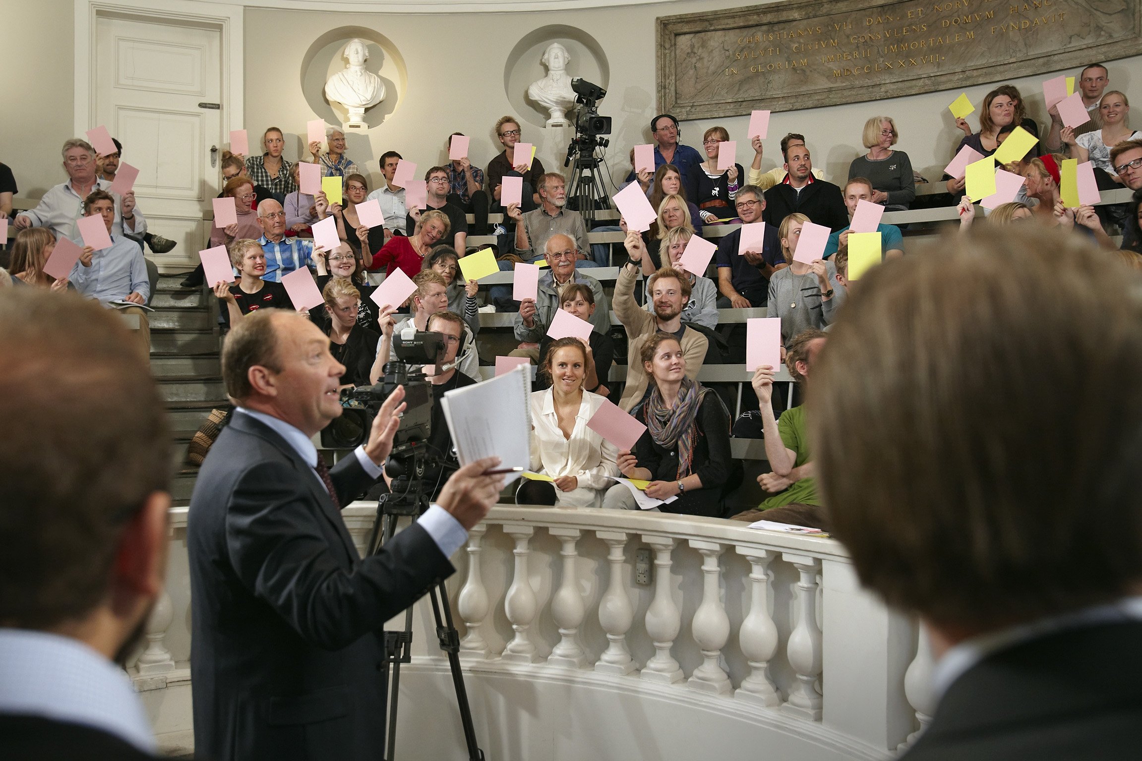 BATTLEMESTER - Jens Olaf Jersild tæller farvede sedler, der indikerer, hvilken side publikum er på. Lyserød er tro, gul er fornuft.