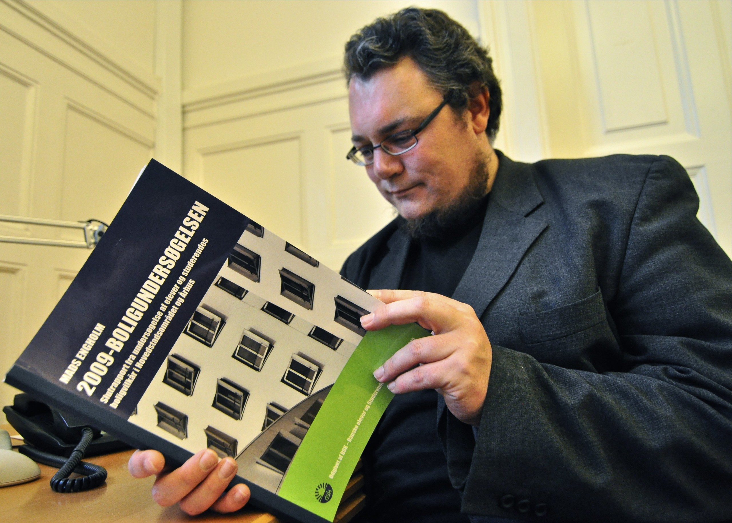Mads Engholm glancing through a report he recently authored on the housing situation for Danish students
