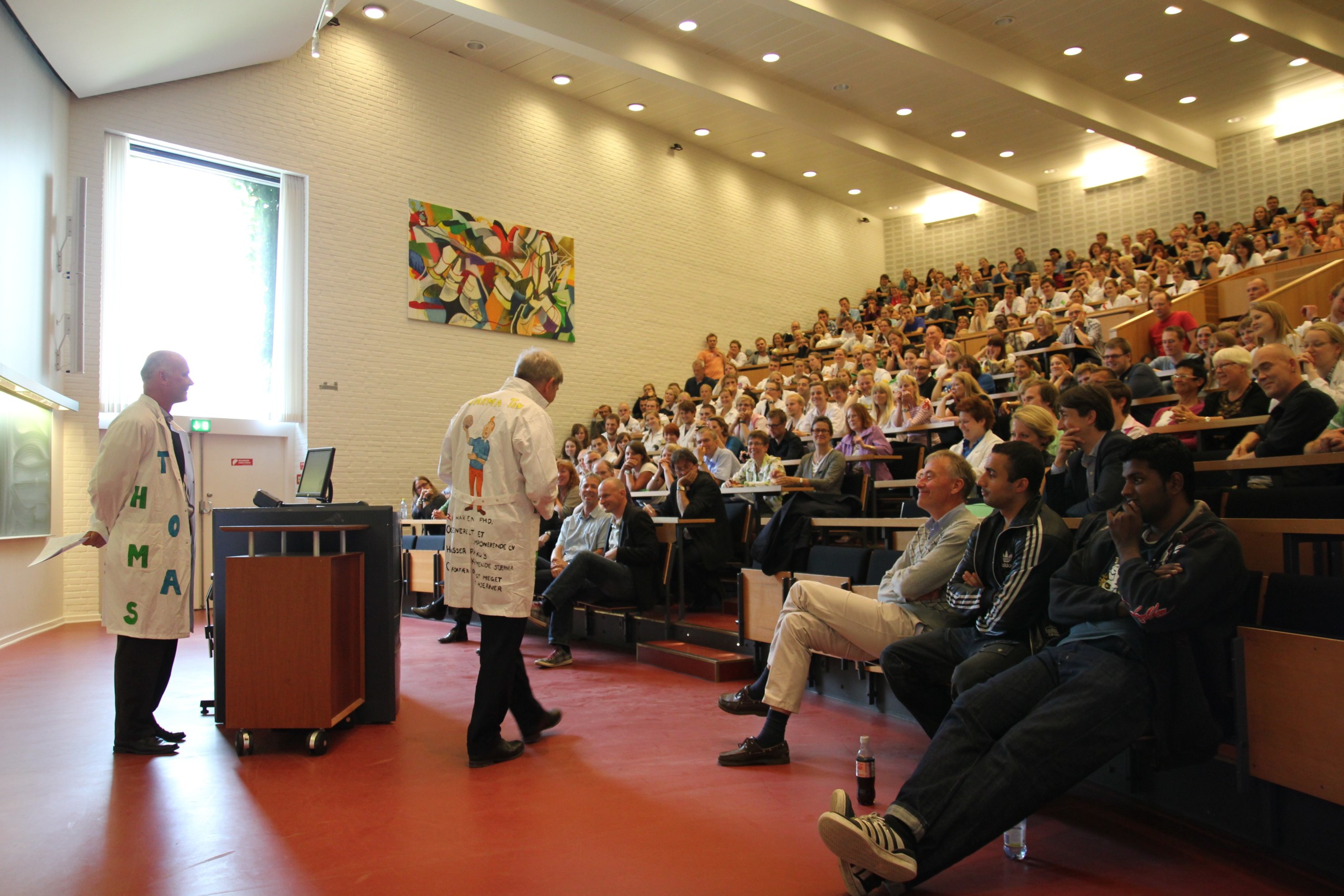 INDFØDT KLÆDEDRAGT - Ralf Hemmingsen og Thomas Bjørnholm (tv) fik klapsalver fra en sal fuld af Farma-studerende og -ansatte, da de iførte sig farmaceutiske laboratoriekitler med unika-dekorationer.