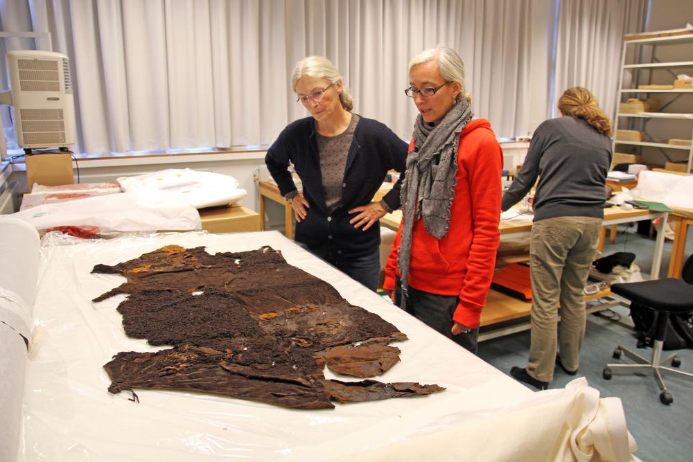 Conservator Anne Lisbeth Schmidt and senior researcher Ulla Mannering from the National Museum of Denmark studying the Huldremose I the 3rd century BC inner cape 