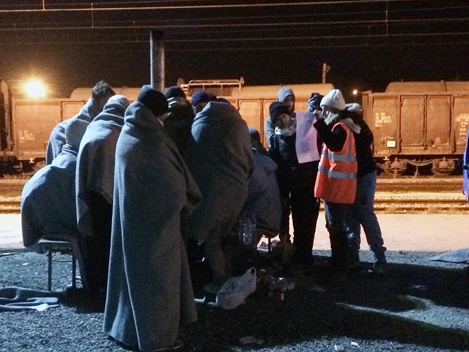 NØDHJÆLP - På en iskold togstation nær den serbisk-makedonske grænse arbejder en frivillig fra nødhjælpsorganisationen 'Balkans Relief' i natten med at vise en gruppe af flygtninge vej. 