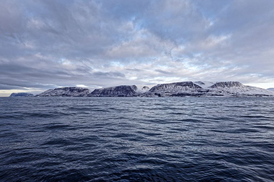 BJERGTAGENDE - Diskoøens kyst set fra havet ud for byen Qeqertarsuaq i retning mod øst