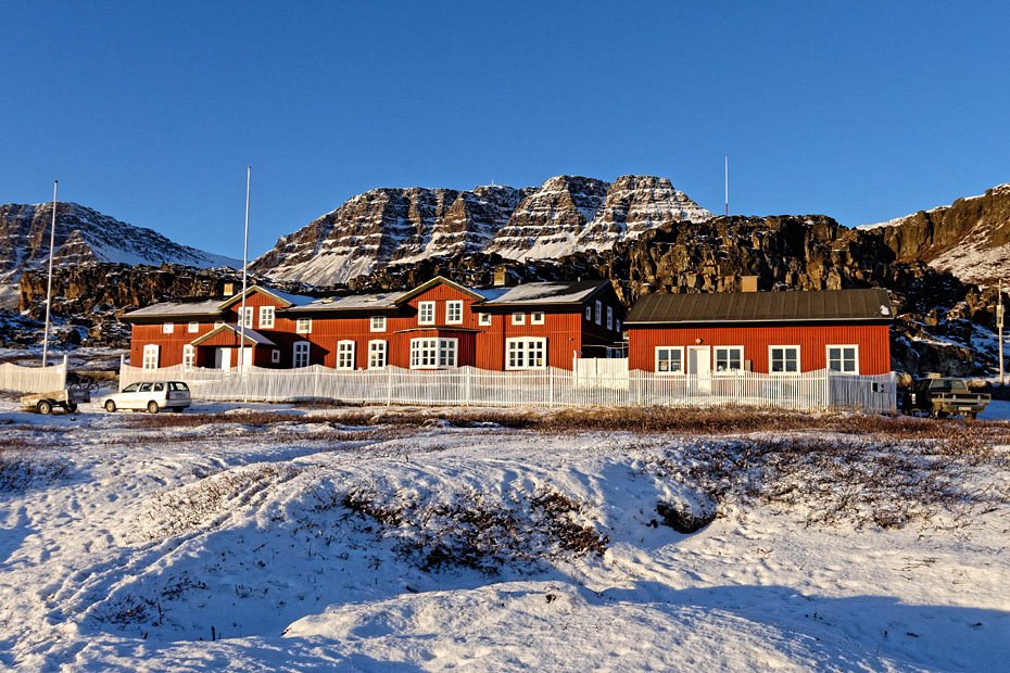 LAV SOL - Arktisk Stations røde træbygninger på Diskoøen set i oktobers lave sol. Den har ligget der i 110 år og er blevet bygget ud undervejs.