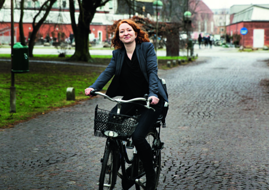 siger Ditte Thøgersen om cyklen, der hver uge bringer hende rundt mellem KU’s campusområder. Hun er gravid med sit andet barn og kører ALTID med cykelhjelm – og har kun under protest indvilliget i at tage hjelmen af til ære for fotografen.