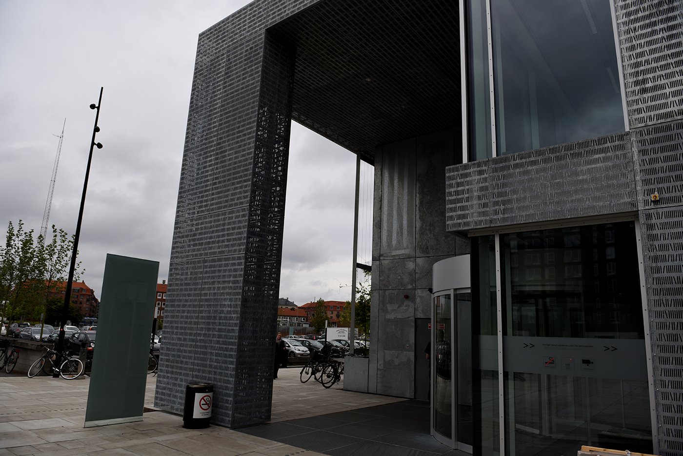 Hovedindgangen på Islands Brygge-siden af Søndre Campus er det eneste overdækkede udendørsareal i et stort brolagt og forblæst område. Det er let at se, hvorfor det er rygernes foretrukne placering på denne side af campus.