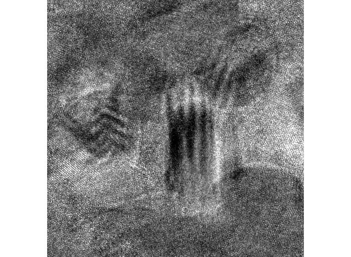 The photo is taken with an electron microscope of a ceramic sample, and every single dot in the image is as small as an atom. The painful mask, which the atoms show, has in this way arisen by chance.