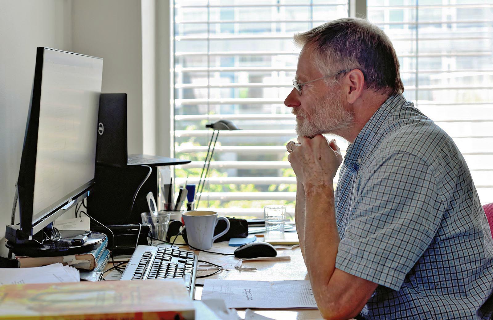 Chistian Troelsgård sidder på sit kontor foran sin pc - billedet her er taget en dag i juni.