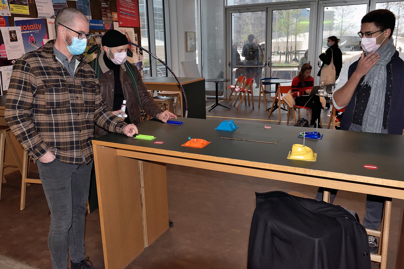 Her er nogen kommet forbi for at spille minigolf - på en meter. Bolden er lillebitte, blå og i luften over den orange forhindring. 