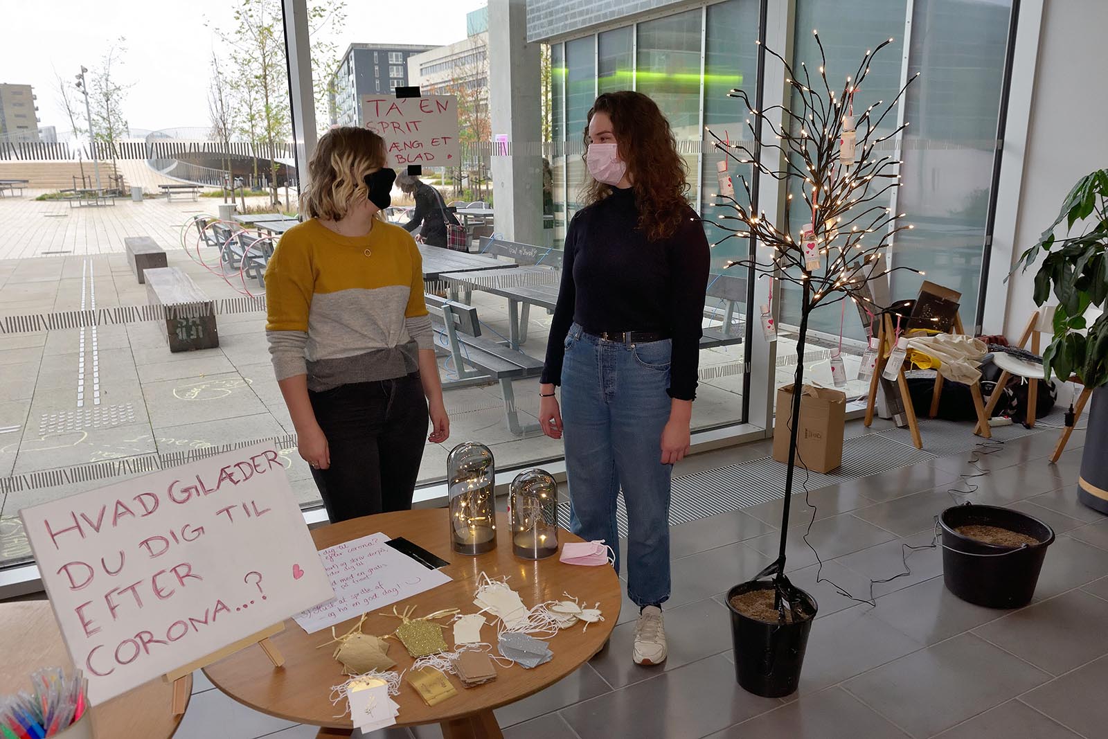 Her er to af arrangørerne foran det indendørs ønsketræ - med lys i.