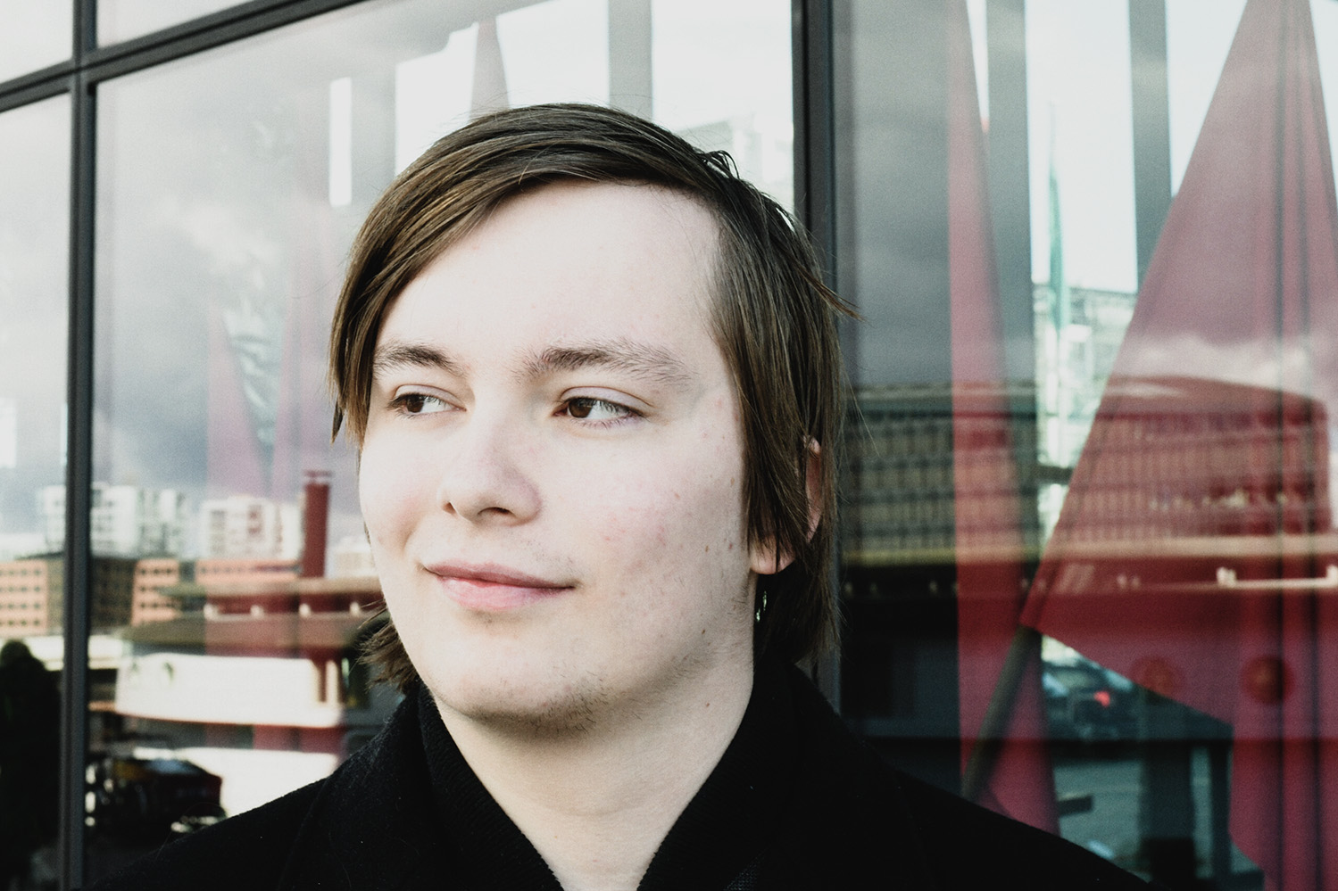 Marcus Guldager foran de røde faner ved Fagbevægelsens Hovedorganisation, hvor han arbejder ved siden af sit studie.