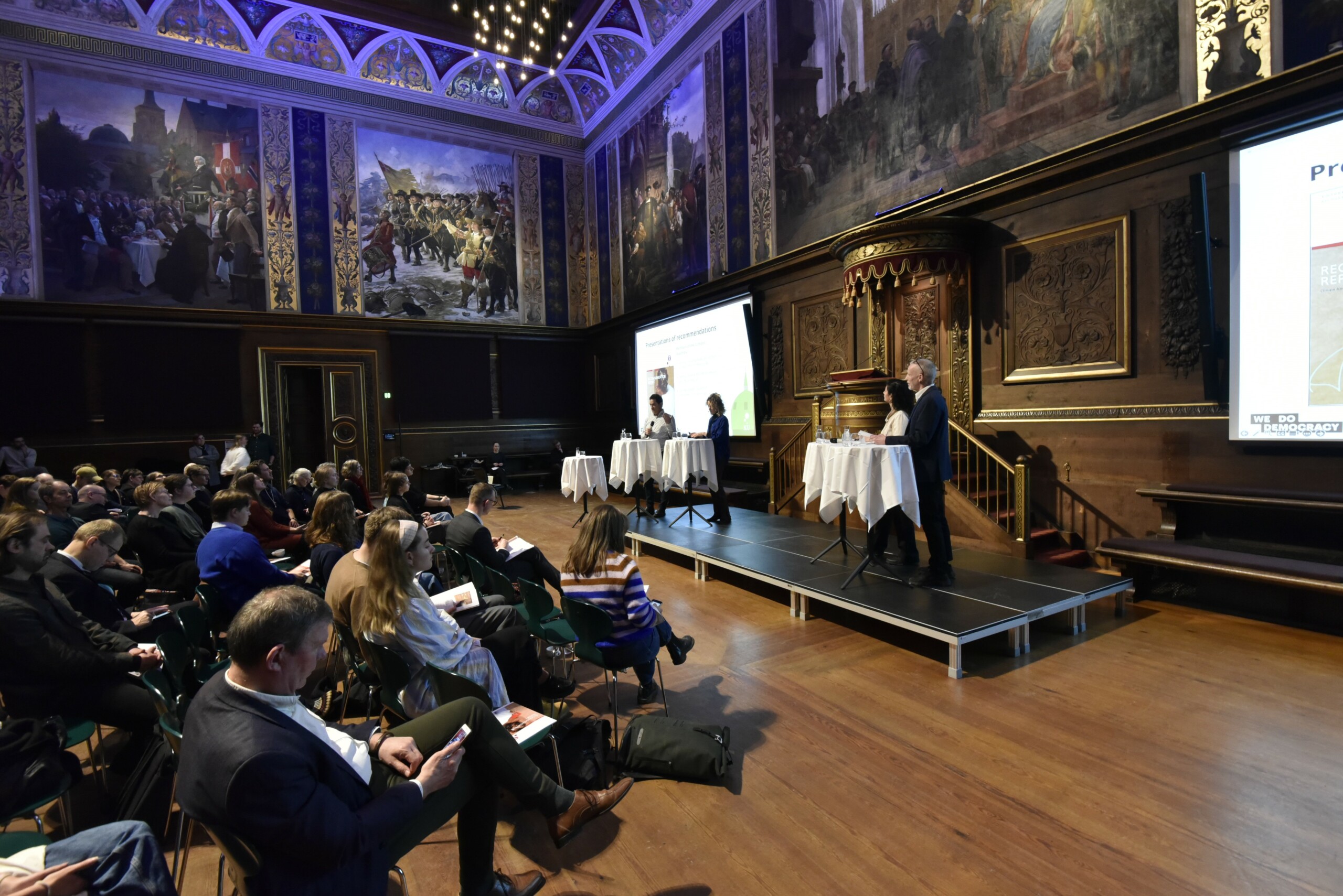 Repræsentanter fra klimasamlingen præsenterer 27 forslag til et grønnere SAMF i KU's festsal.