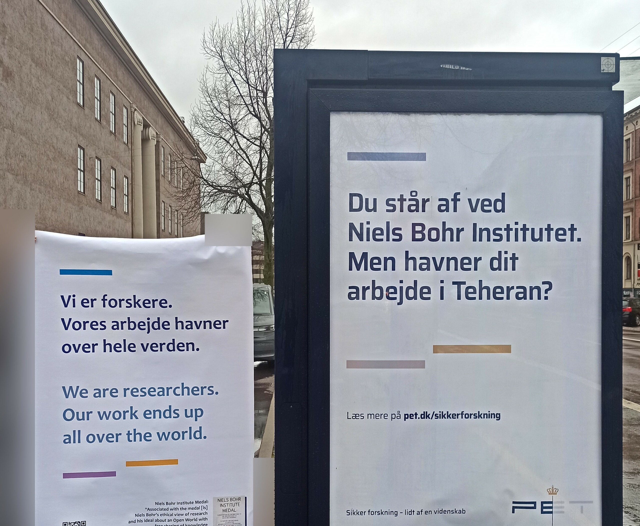 »Vi er forskere. Vores arbejde havner over hele verden.« I yderligere protest har en håndfuld af forskerne lavet deres egen plakat, som de her holder op ved siden af PET-kampagnen. 
