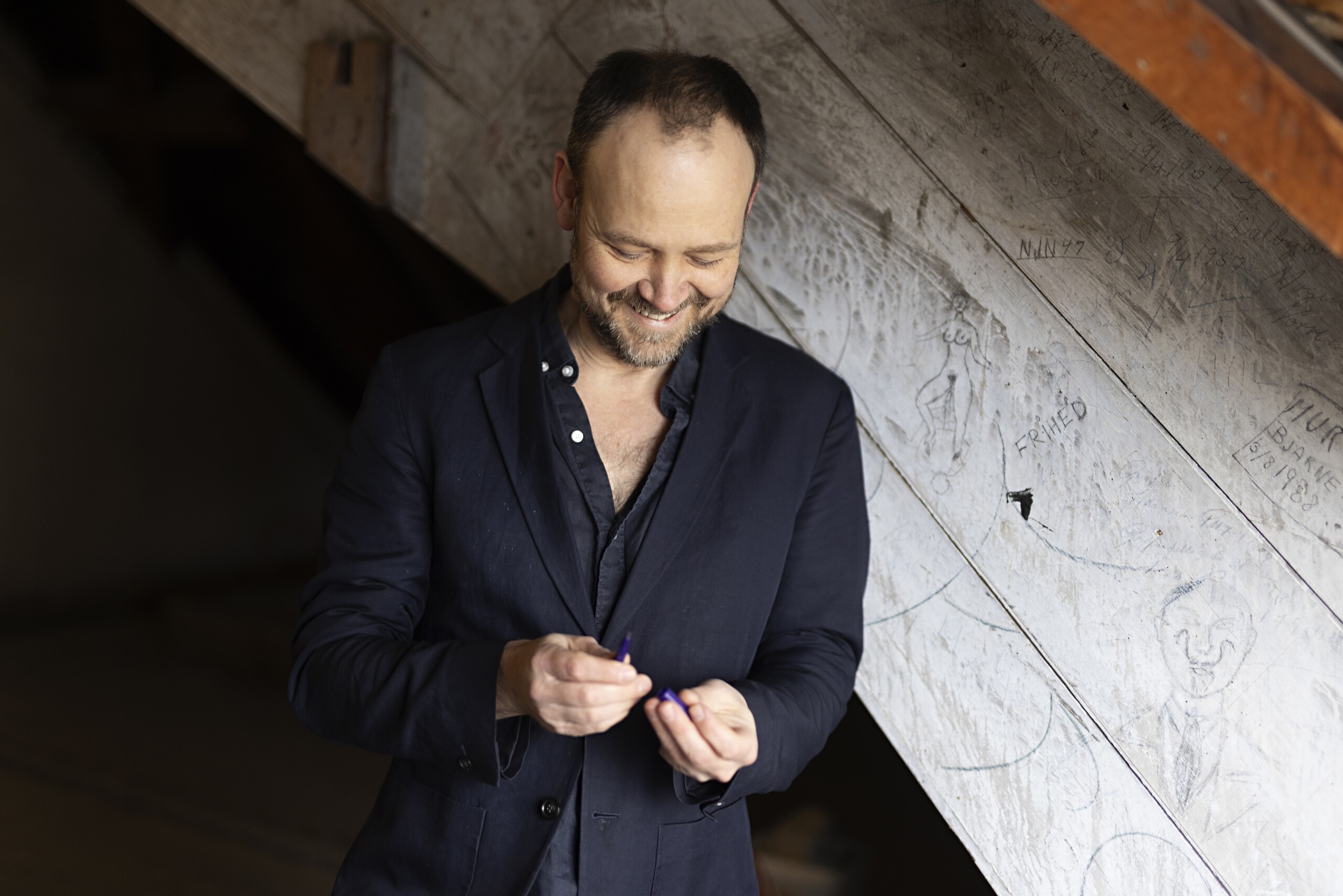 Christoffer Zieler på loftet over KU’s gamle festsal. Til hans begejstring har forbipasserende ytret sig på væggene deroppe i både ord og tegning. Han hev selv en pen op ad inderlommen til ære for fotografen.