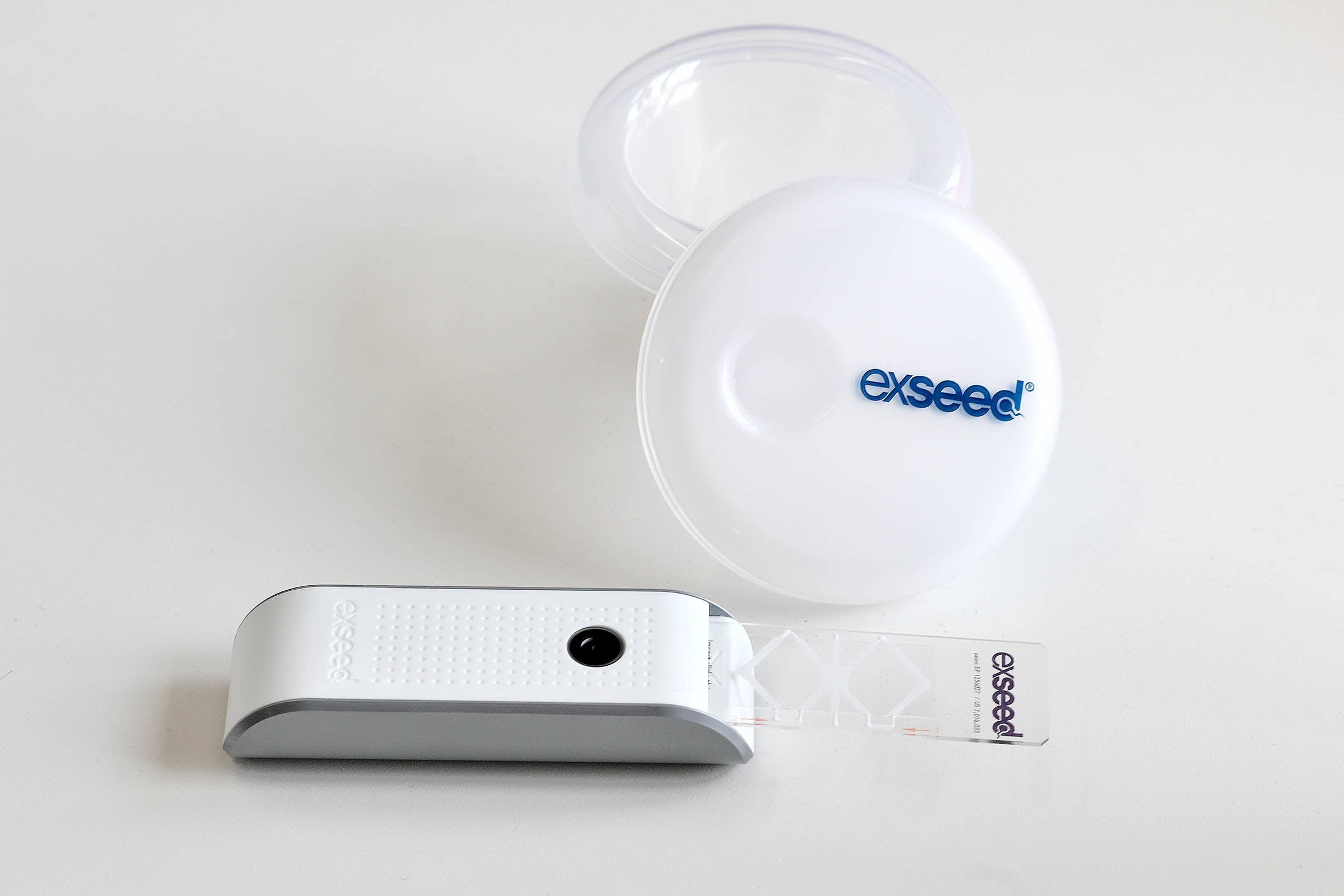 Skålen bagest er til opsamling af sæd, hvoraf lidt lægges imellem de to objektglas, der følger med testkittet. Objektglassene skubbes ind i apparatet, der blandt andet indeholder en lyskilde og en linse til at forstørre prøven med.