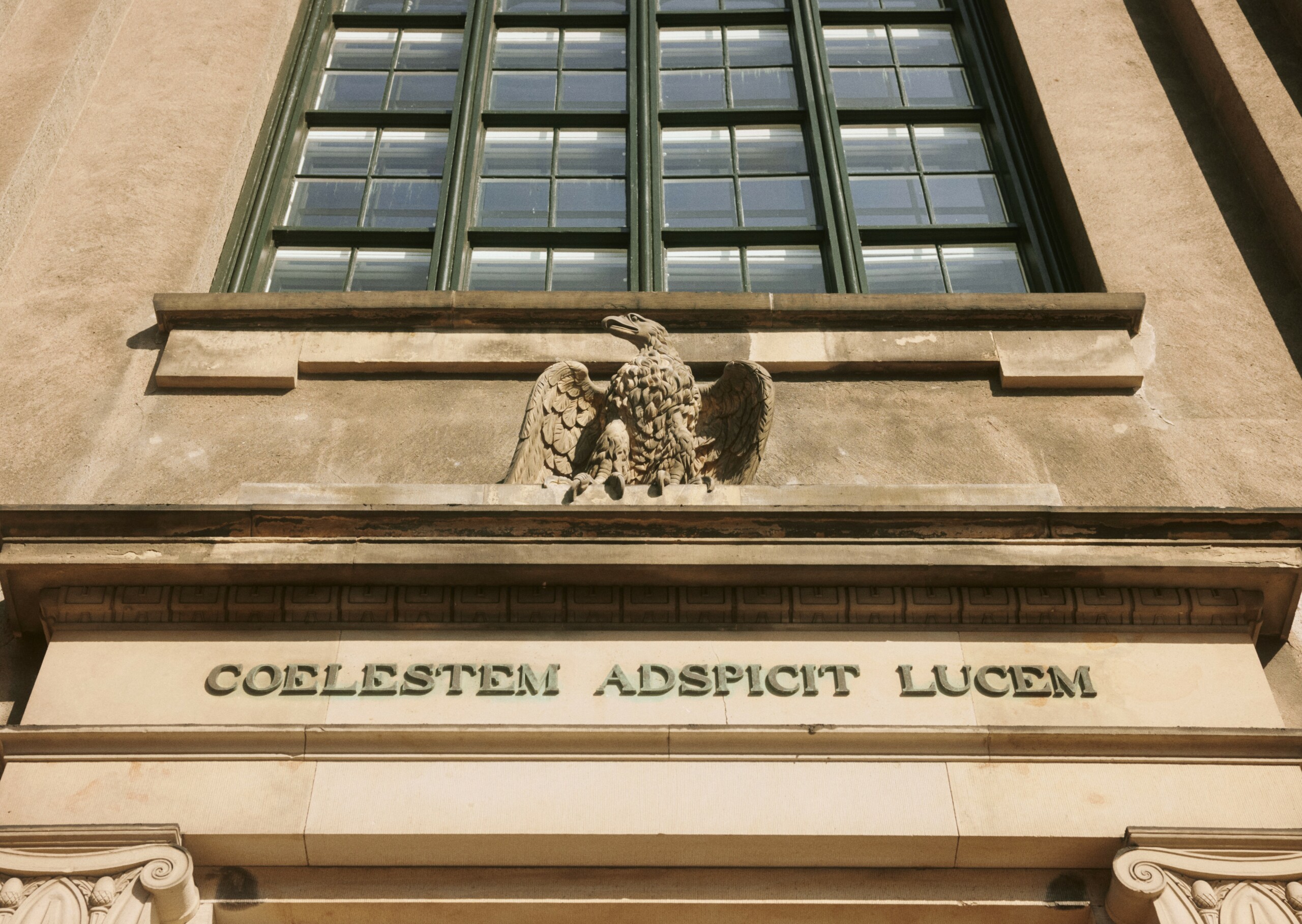 KU's motto Coelestem adspicit lucem (Den skuer det himmelske lys) ses over indgangen til hovedbygningen.