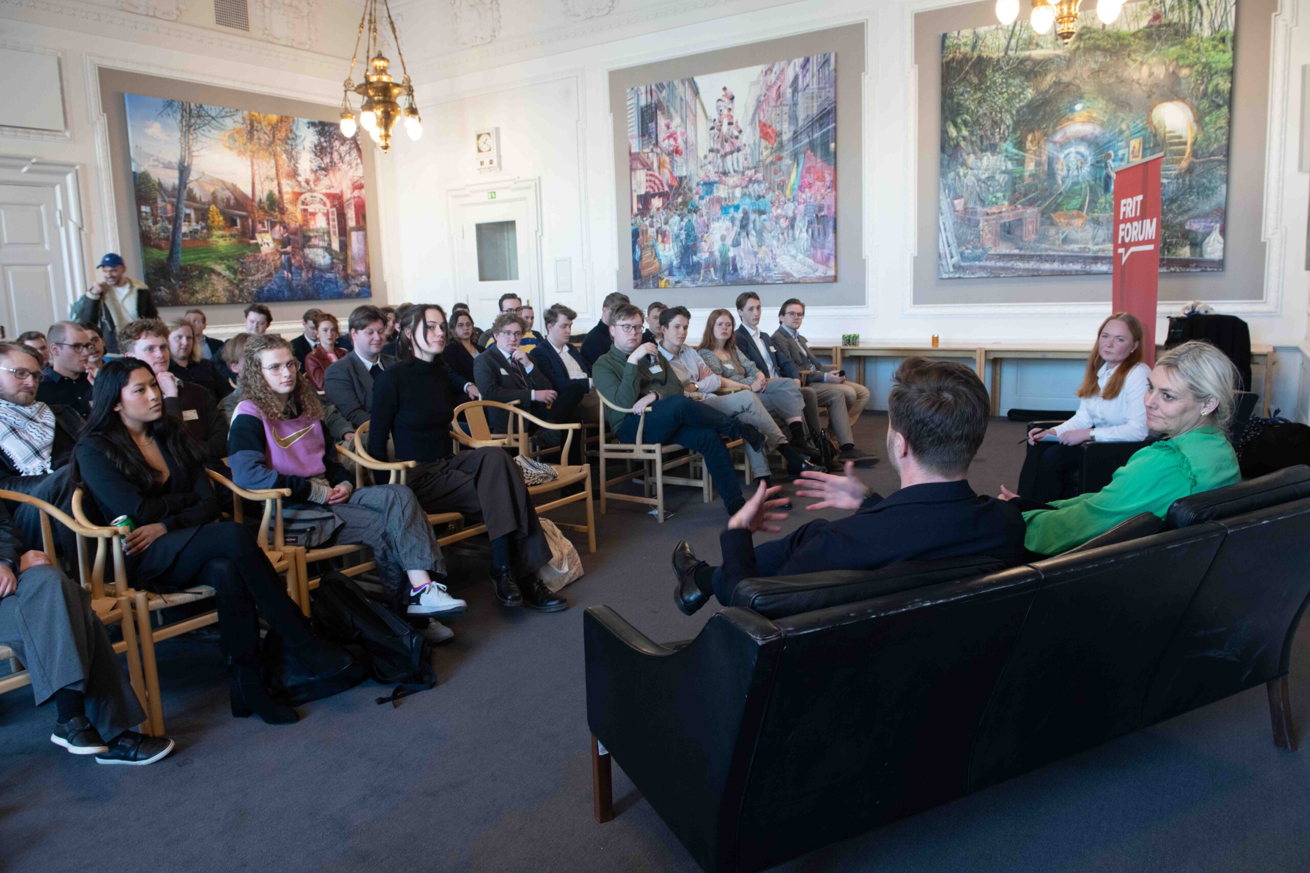 De fremmødte lytter til tidligere erhvervsminister Simon Kollerup og tidligere forsvarsminister, transportminister og minister for ligestilling Trine Bramsen (henholdsvis til venstre og højre i sofaen). Tidligere landsformand for Venstres Ungdom Maria Ladegaard modererer samtalen.