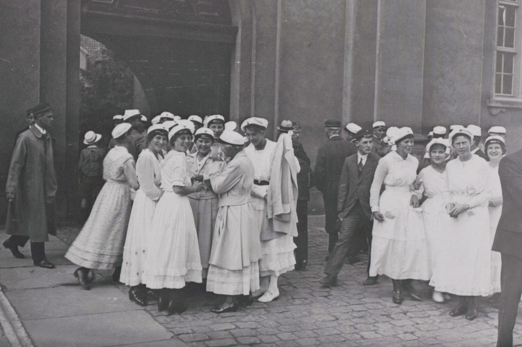 Immatrikulation på Københavns Universitet for nye studerende mellem 1900 og 1945, det præcise årstal er ukendt. Kvinderne er klædt i hvidt, mens mændene er i mørke klæder.